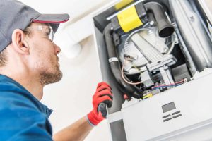 Technician and the Heater Issue. Caucasian Worker Looking Inside Central Gas Heater Trying to Fix the Problem.